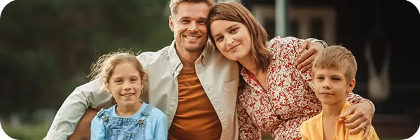 Mom, Dad and two kids posing for a picture in the park.