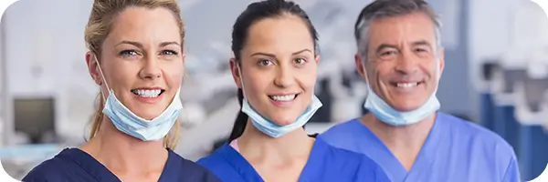 Three dentists smiling in the waiting room of their office.