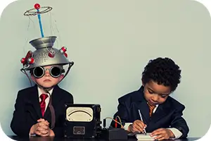 Two kids with home made brain detector playing at a table.